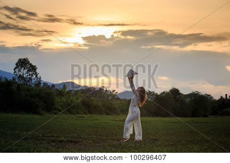 Blonde Girl In Vietnamese Dress Lifts Hat Above Head On Field