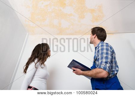 Worker Writing On Clipboard With Woman In House