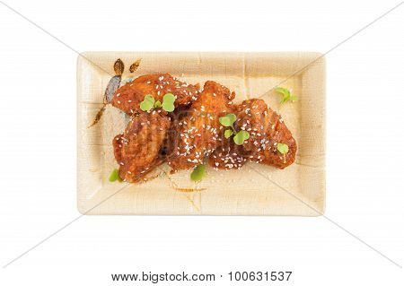 Korean fusion style deep fried chicken wings seasoned with Korean spicy kimchi sauce on square ceramic dish