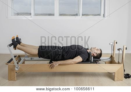 Man Doing Pilates In Reformer Bed.