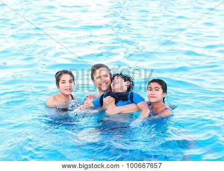 Multiracial Family Swimming Together In Pool. Disabled Youngest Son.