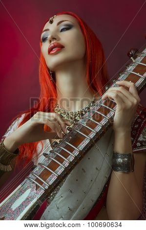 Beautiful Redhead Woman In Indian Sari With Oriental Jewelry Playing The Sitar