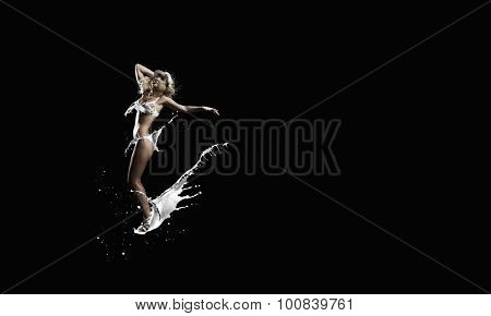Hot young dancing woman in white bikini on dark background