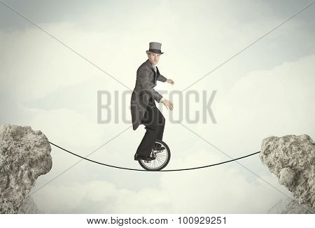 Brave business man riding an mono cycle between cliffs concept