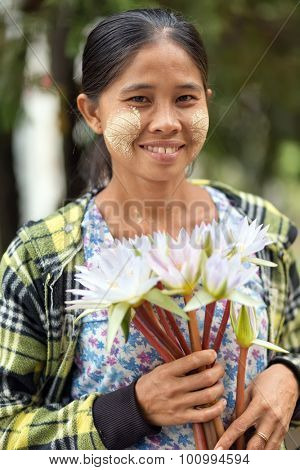 MANDALAY,MYANMAR,JANUARY 17, 2015 : Portrait of a woman with thanaka powder leaf patterns, selling waterlily flowers at the entrance of the pagoda Kuthodaw, in Mandalay, Myanmar (Burma).