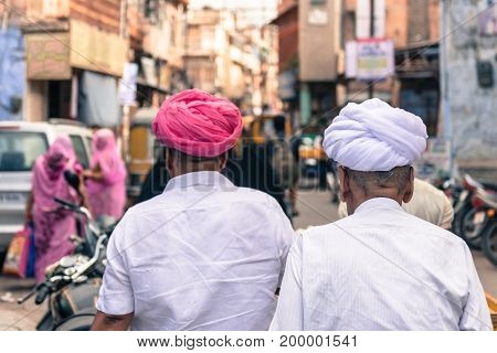 JODHPUR RAJASTHAN INDIA - MARCH 04 2016: Picture from the back of two old men dressing colorful turbans in old Jodhpur the blue city of Rajasthan in India.