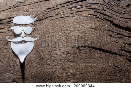 Hipster's definicial facial look cut from paper on the wooden background.