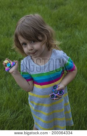 Little girl playing with fidget spinner. Child spinning spinner in park.