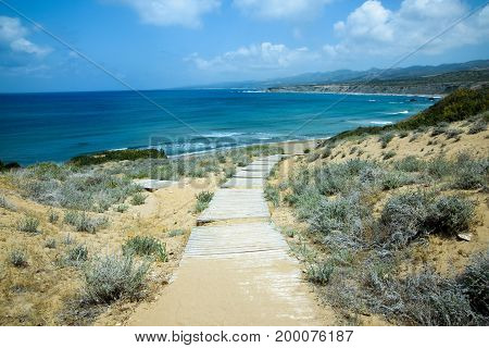 sunny wooden boardwalk to the wild beach