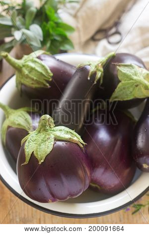 Aubergines In A Bowl On A Wooden Table. Vertical. Selective Focus.