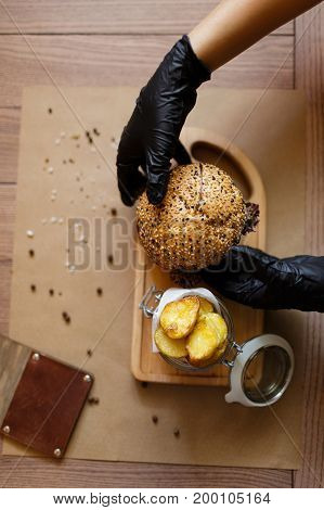 A top view of a fresh juicy meat burger and rustic potatoes on a wooden cutting desk. Fast food composition on a wooden table background, close-up. American burger. Cooking, fast food, concept.