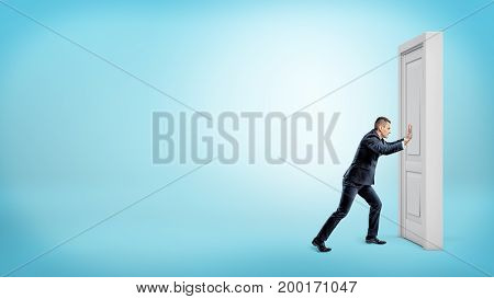 A small businessman pushes a closed door on a white wooden door frame. Business struggles. Strength for success. Opening closed doors.