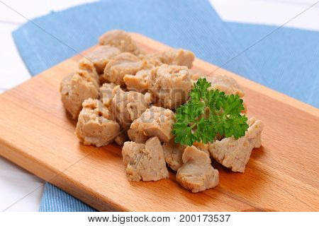 pile of soy meat cubes on wooden cutting board - close up