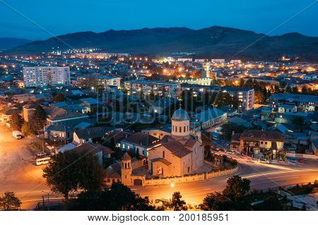 Gori, Shida Kartli Region, Georgia. Gori Cityscape In Evening Illumination Under Blue Sky In Twilight. Cathedral Of The Blessed Virgin Mary In Night Illuminations Lights. Travel Destination