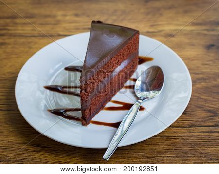 Delicious chocolate cake with spoon on white plate