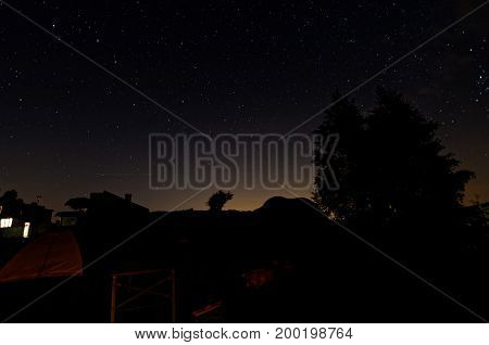 Shadows of sjelter and tents on top of the mountain. Summer time. Beautiful starry night.