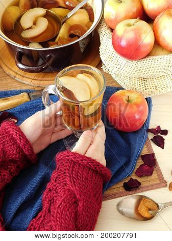 Apple compote. Female hands are holding a glass of warm compote