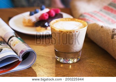 Cappuccino cake with berries and a journa on table. Closeup.