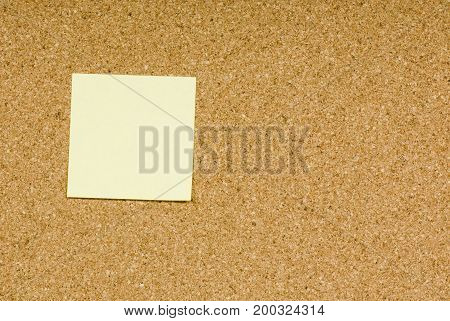 Blank sticky note on a cork bulletin board