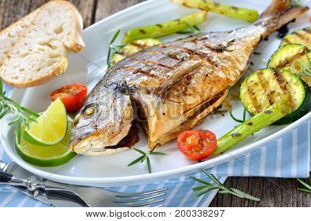 Grilled gilthead seabream with mixed rosemary vegetables served on an oval white fish plate