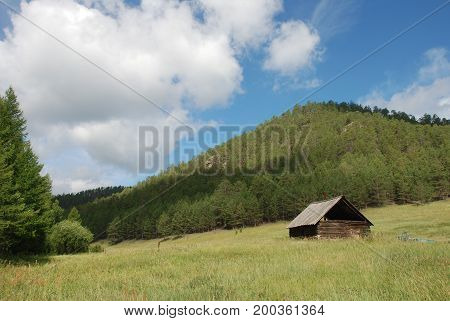Old hut in the mountains against the backdrop of the forest