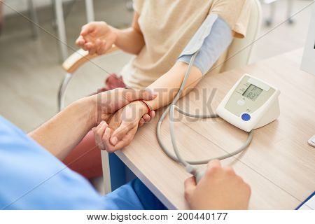 Closeup image of doctor measuring blood pressure of female patient using automatic blood pressure monitor