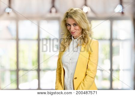 Beautiful shy girl looking at camera. Beautiful embarrassed blonde woman in formal wear posing on blurred background.