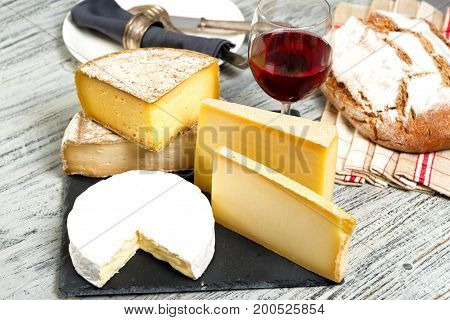 Different french cheeses with a glass of red wine