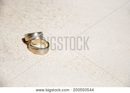 Wedding rings on sand in the sun