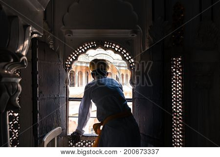 JODHPUR RAJASTHAN INDIA - MARCH 05 2016: Wide angle picture of indian man with turban looking at the window at Mehrangarh Fort in Jodhpur the blue city of Rajasthan in India.