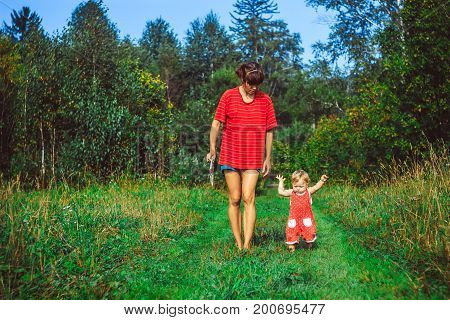 The child learns to walk in the park barefoot on the grass
