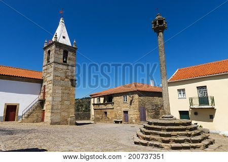 View of the central square of the historic village of Castelo Mendo in Portugal with a church and pillory; Concept for travel in Portugal