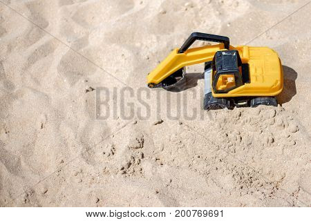 The excavator toy on the beach working with sand. industrail symbols