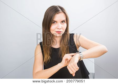 Time is over. Attractive brunette woman pointing to her hand reminding about time.