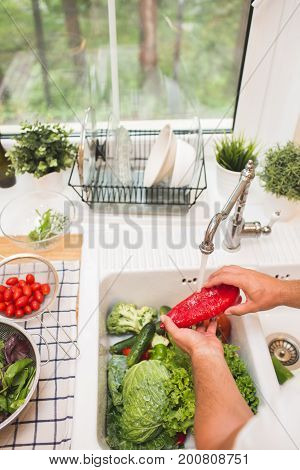 Man washes vegetables on the kitchen before eating