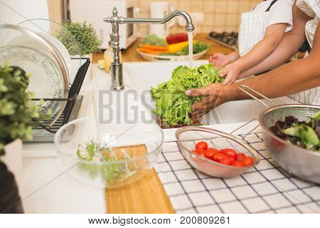 Father with little son washes vegetables on the kitchen before eating