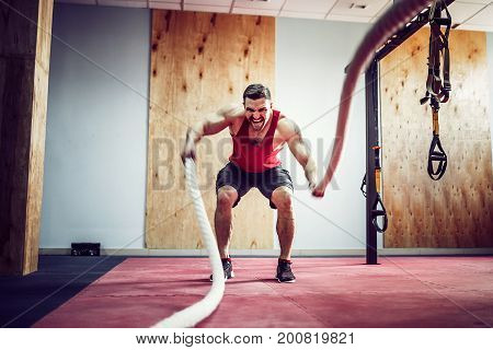 Men with battle rope in functional training fitness gym