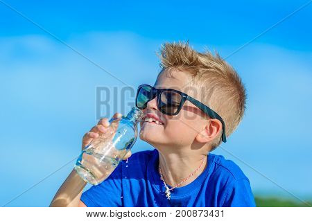 Portrait Of A Thirsty Handsome Boy In Sunglasses Drinking Water On The Desert Tropical Beach