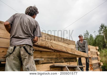 Russia Siberiya - 1.09.2013: Construction worker framing the roof of a country house with help of a crane