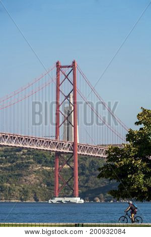 Beautiful view of the red bridge, Ponte 25 de Abril in Lisbon. The bridge connects two cities across the river. Concept of architecture, construction, transportation