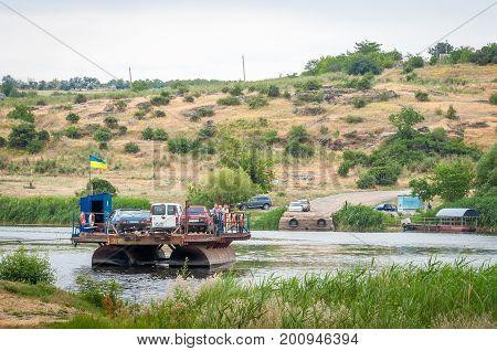 Ukraine Southern Bug River - 18 June 2017: Ferry crossing. The ferry moves with the help of a man's muscular strength. Repels from the steel cable. Such a ferry is unique in Ukraine.