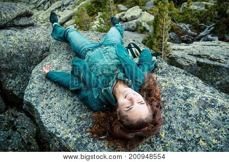 beautiful brunette girl in black clothes posing on a huge rock among stones