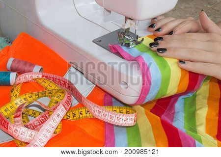 Woman hand on sewing machine.Dressmaker work on the sewing machine. Hobby sewing fabric as a small business concept. Female tailor threading leather material on sewing machine