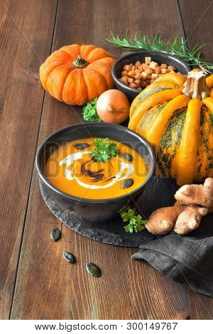 Spicy Pumpkin Soup With Ginger And Onion, Served In Black Bowl With Pumpkin Oil, Cream, Pumpkin Seed