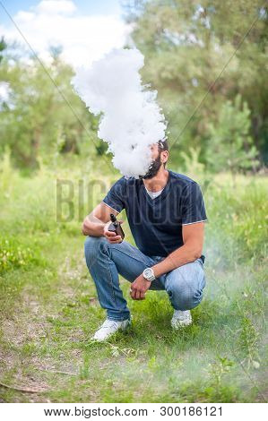 Handsome Man Smoke Electronic Cigarette And Exhals Smoke Cloud. Vape.