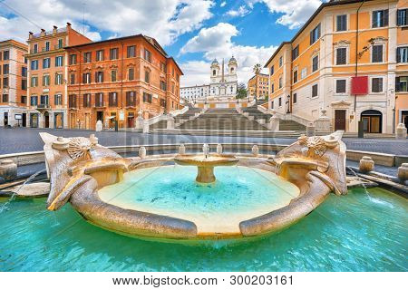 Rome, Italy. Fountain of the Boat (Fontana della Barcaccia) on Spanish square (Piazza di Spagna) at the bottom of Spanish stairs famous landmark design by Bernini. Summer day and blue sky with clouds.