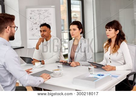 new job, hiring and employment concept - international team of recruiters with tablet pc computers having interview with male employee at office