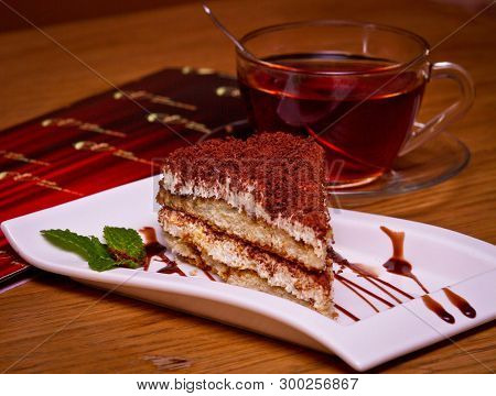 Tiramisu Cake With Biscuit On A Plate With A Spoon And A Cup Of Tea