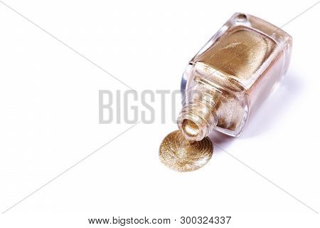 Bottle Of Golden Glitter Nail Polish Spilled On The Plain Surface. Isolated Object On White Bcakgrou