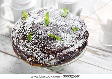 Chocolate Cake With A Chocolate Coating And Coconut Chop Decoration.